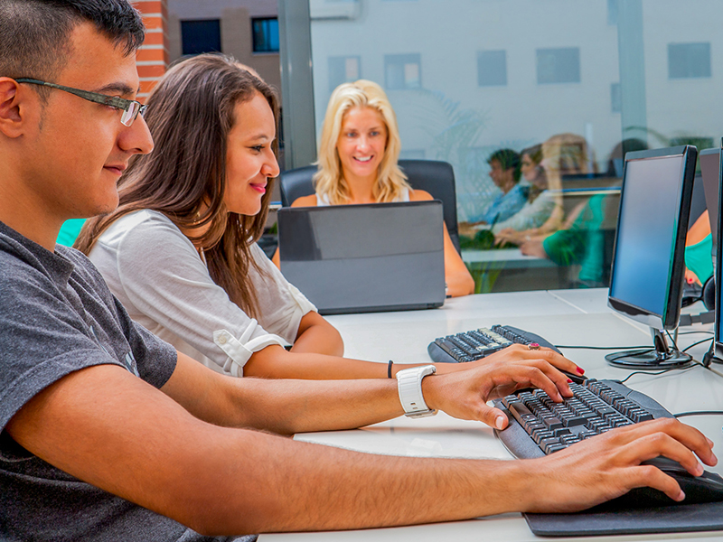 Students gathered at computers working on business plan ideas.
