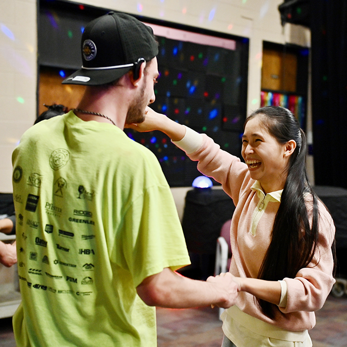 asian student smiling and dancing with male student