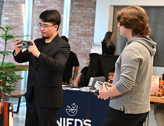 Broadcasting Digital Media male student recording on camera and another student helping