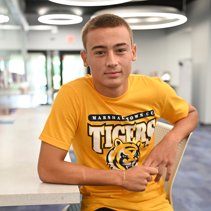 male student sitting in library smiling