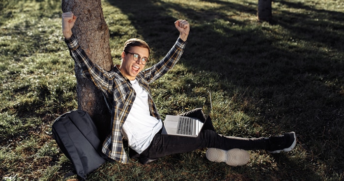 guy-celebrating-with-arms-up-laptop-on-lap