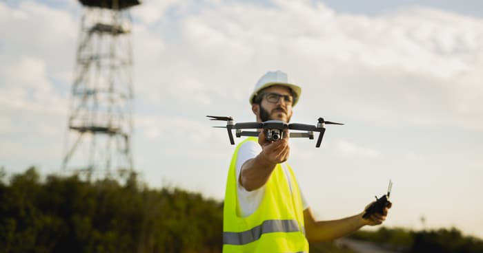 man-in-safety-vest-holding-drone