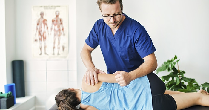 male-medical-person-stretching-females-back