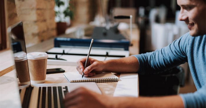 male-at-desk-writing-with-laptop