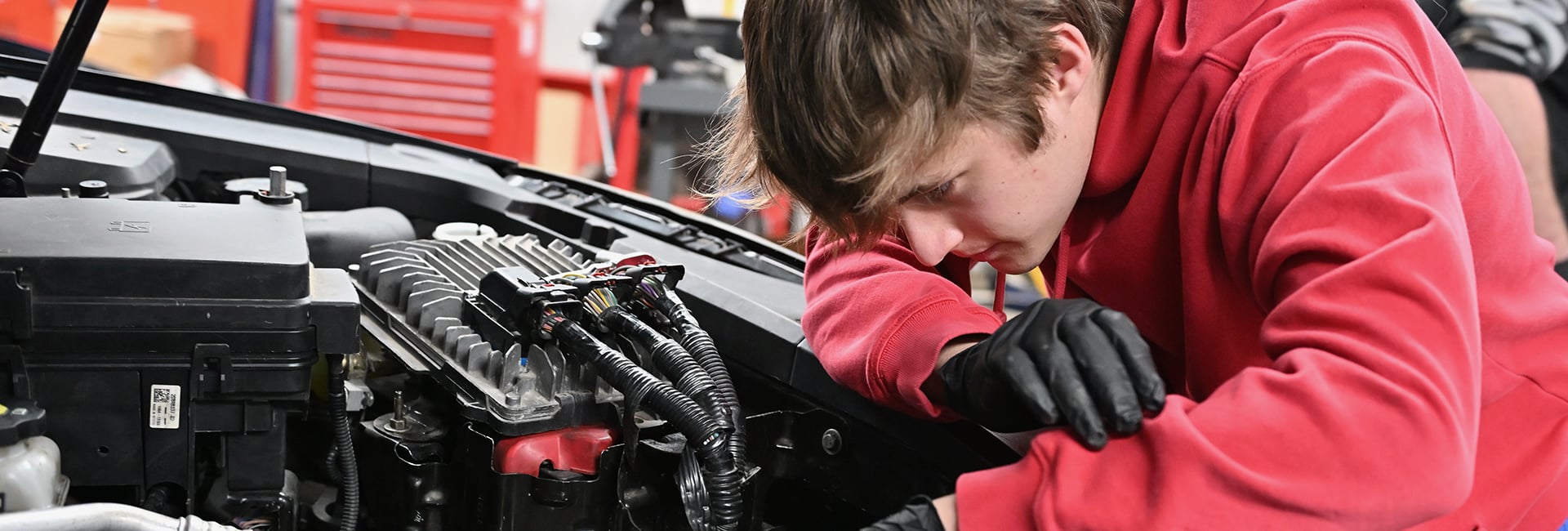 student-working-under-car-hood